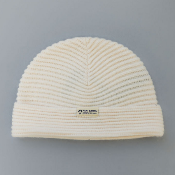 A ribbed cream beanie with a white woven patch with the Moterra Campervans logo stitched onto it.